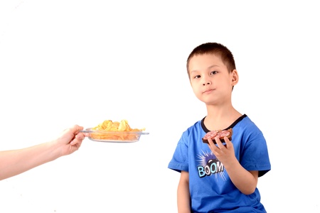 A Chinese child eating a sandwich and a hand with a plate of chips