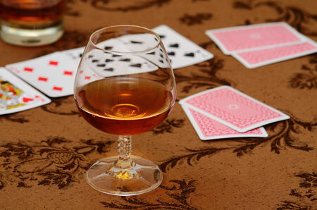 Goblet of brandy on the table with cardsの写真素材