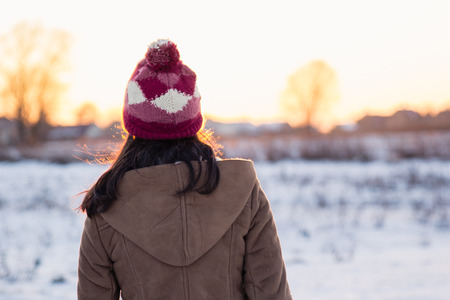 Teenage girl enjoys bright sunset lights in winter