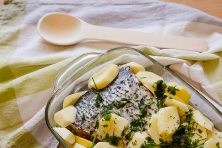 Fish filet with potatoe and parsley ready for baking on wooden table backgroundの写真素材