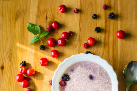 Raspberries and brambles with cereal porridge on wooden tableの写真素材