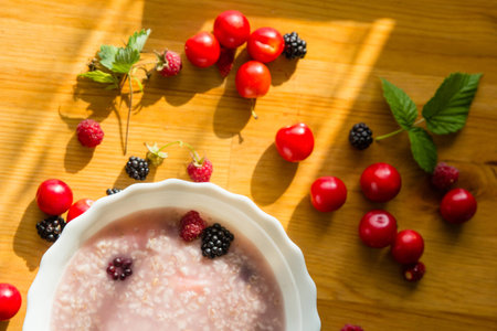 Raspberries and brambles with cereal porridge on wooden tableの写真素材
