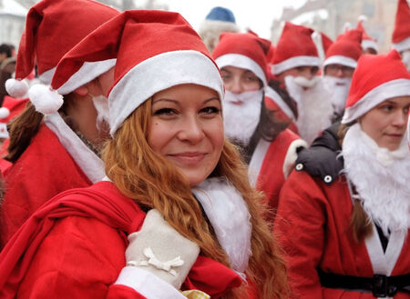 Uzhgorod,Ukraine-December 17, 2010: Smiling girl dressed as a Santa Claust in the front of group of other peaple dressed the same during Santa Claus parade December 17,2010 in Uzhgorod. Ukraineのeditorial素材