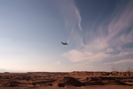 Plane flyes over the desert in the eveningの写真素材