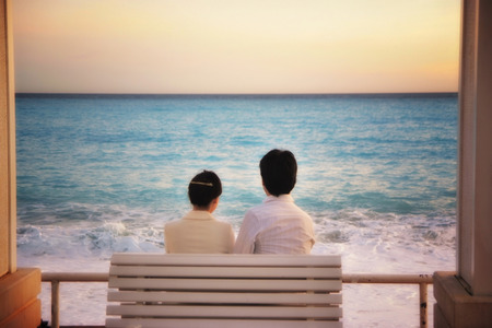 back view of  asian romantic couple looking on the sea, soft focus styleの写真素材