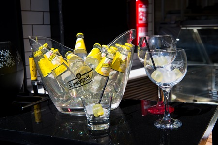Key west, Fl, USA - March 30, 2016: Schweppes Tonic Water bottles yellow color in glass with cold ice cubes on table near bocals of lemon beverage with drinking strawのeditorial素材