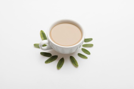 White cup with coffee with milk, cappuccino or latte and leaves on white backgroundの写真素材
