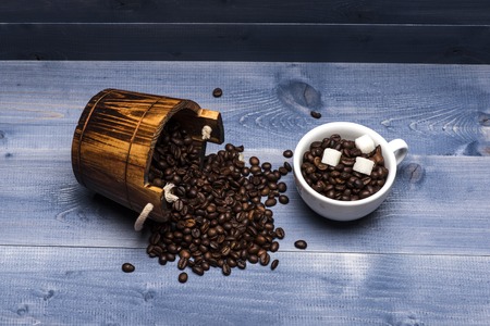 Coffee beans set up on wooden cask and coffee cup with coffee beans and sugar cubes on vintage wooden background. Top viewの写真素材