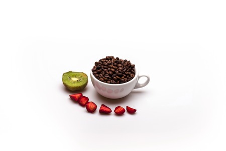Roasted coffee beans in a white ?up with kiwi and strawberry on white background. Side viewの写真素材