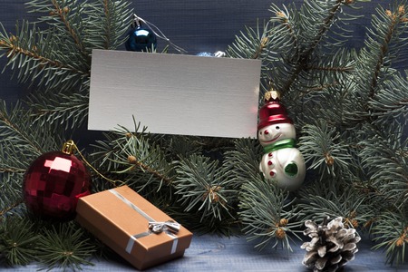 Christmas baubles and decorations including gift with silver bow, christmas tree, snowman toy, leaf, brown pine cone and christmas balls on vintage wooden background, copy spaceの写真素材