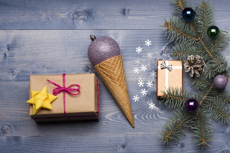 Christmas baubles and decorations including gift with rose thread, golden yellow bow, gift with silver bow, snowflakes, violet silver christmas ball, ice cream cone, christmas tree with brown pine cone and balls on vintage wooden backgroundの写真素材