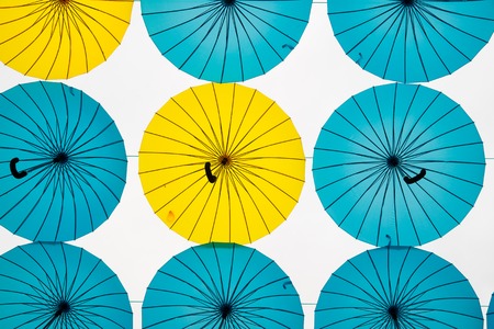 Collection of multi colored umbrellas hanging up in an open position over a street offering shade and protection from the elements.の写真素材