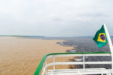 water meeting in brazil -amazon river with rio del negro clean and dirty river water with different...