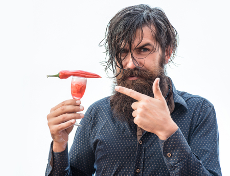 handsome bearded man with wet ruffled hair mustache and long beard on happy face holding glass of red alcoholic beverage with chili isolated on whiteの写真素材