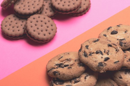 Chocolate chip cookies placed on opposite sides on colorful orange pink backgroundの写真素材