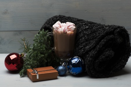 Cacao or chocolate with marshmallows in glass, scarf, christmas balls, pine branch and coffee cup, set of christmas decoration on wooden background. Side viewの写真素材