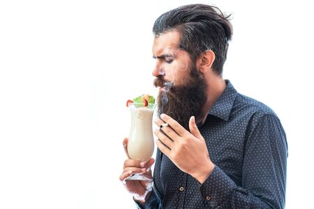 handsome bearded man with stylish hair mustache and beard on serious face holding glass of nonalcoholic beverage and smoking cigarette isolated on white, copy spaceの写真素材