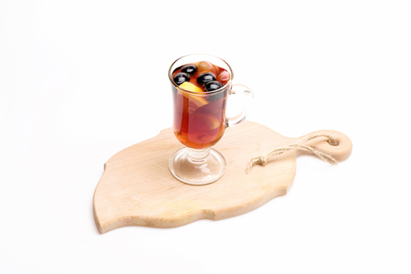 Glass of delicious glintwein or mulled hot wine on cutting board with thread isolated on white backgroundの写真素材