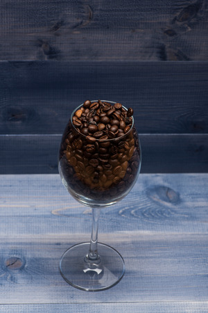 Roasted coffee beans inside wine glass on vintage wooden background. Side viewの写真素材