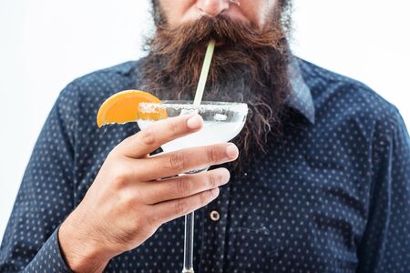 handsome bearded hipster with stylish mustache and beard on face holding glass and drinking alcoholic beverage isolated on whiteの写真素材