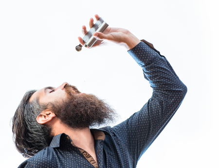 handsome bearded fashion man with stylish hair mustache and long beard on serious face drinking from metallic flask isolated on whiteの写真素材