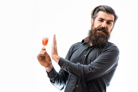 handsome bearded man with stylish hair mustache and long beard on dissatisfied face holding glass of red alcoholic beverage isolated on whiteの写真素材