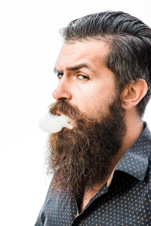 handsome bearded fashion man with stylish hair lush mustache and long beard on serious face smoking cigarette isolated on whiteの写真素材