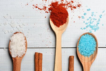 Set of ingredients for cooking of salt, cinnamon, paprika, spices and wooden spoons on vintage wooden white backgroundの写真素材