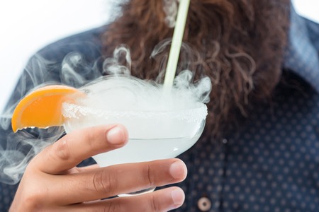 bearded man with lush beard holding glass of alcoholic beverage with thick smoke and orange isolated on whiteの写真素材