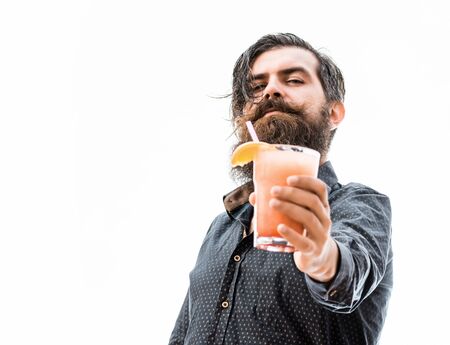 handsome bearded man with stylish hair mustache and long beard on serious face showing glass of nonalcoholic cocktail isolated on white, copy spaceの写真素材