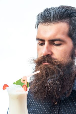 handsome bearded man with stylish hair mustache and long beard holding and looking on glass of nonalcoholic cocktail isolated on whiteの写真素材