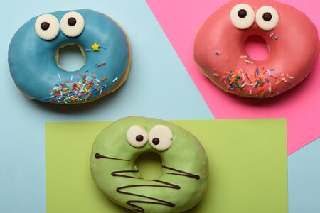Colorful funny glazed donuts with icing or sprinkles and chocolate on colorful backgroundの写真素材