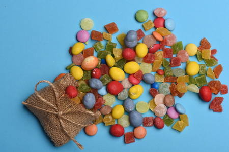 Mix of colorful dragee with raisins or peanuts inside, marmalade or jelly candies and knitted bag...
