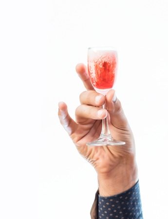 strong male hand carefully holding glass of red alcoholic beverage isolated on whiteの写真素材