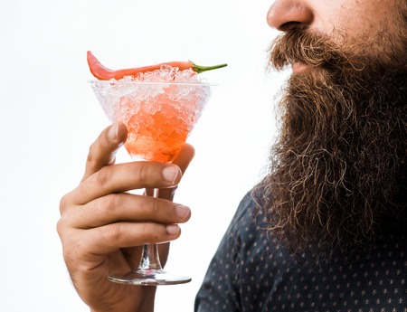 bearded man with lush beard holding glass of alcoholic cocktail with red chili and ice isolated on white, close upの写真素材