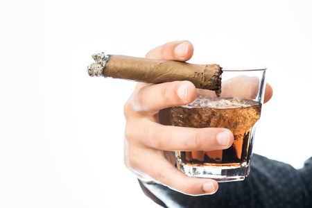 strong male hand holding glass of whiskey with ice and set on fire cigar isolated on white , close upの写真素材