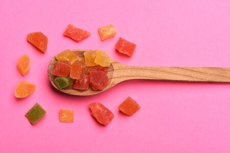 Colorful marmalade or jelly candies, wooden spoon on pink background