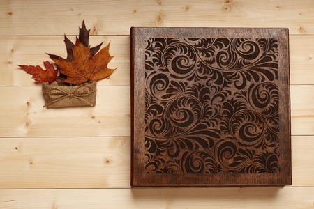 Brown wedding album with photos, knitted bag and maple leaves on vintage wooden backgroundの写真素材