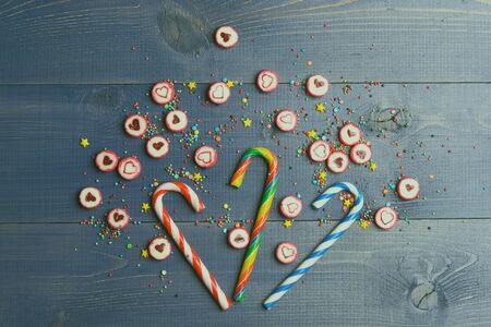 Set of striped caramel candies, candies with valentine heart sign and colorful sprinkles on vintage wooden background, top viewの写真素材