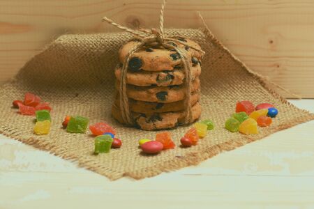 Oatmeal chocolate cookies with thread, colorful dragee, marmalade or jelly candies and knitted...