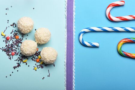Set of white coconut candies and striped caramel candies with sprinkles and purple ribbon on...