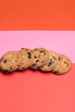 Chocolate chip cookies placed in row on each other on colorful red pink backgroundの写真素材