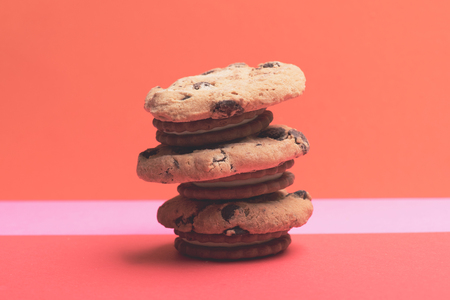 Chocolate chip cookies made up on each other in form of tower on colorful red pink background, side viewの写真素材