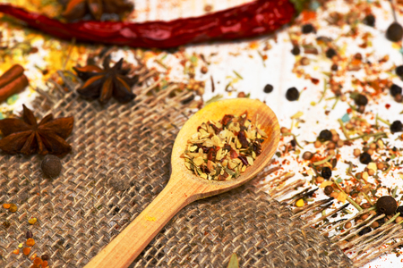 set of ingredients for cooking spicy fragrant spices in spoons with cinnamon and chili pepper on net sacking and vintage wooden background, side viewの写真素材