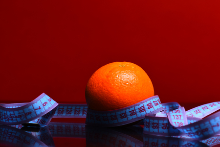 orange with measurement tape around in red background, copy spaceの写真素材