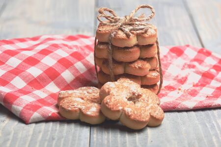 freshly baked tasty homemade stars cookies with powdered sugar on checkered napkin on grey vintage wooden background, side viewの写真素材