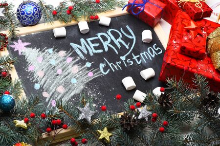 set of christmas or new year decoration with green fir tree with silver golden stars, colorful presents or gifts with xmas balls and black board on white vintage wooden background, copy spaceの写真素材