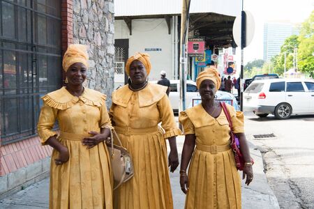 Port of spain, Trinidad and Tobago - November 28, 2015: three smiling woman african American in yellow traditional dress costumes with turban hat outdoor in streetのeditorial素材