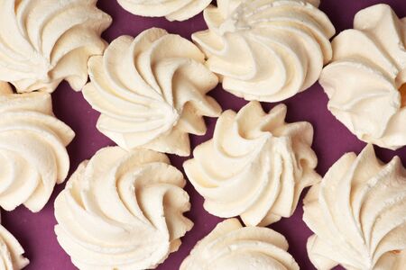 set of white sweet marshmallows or zephyr laying on purple background, top view