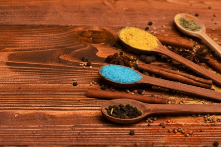 set of ingredients for cooking spicy fragrant spices in spoons with coriander and pepper and curry and cinnamon and salt on vintage wooden background, copy spaceの写真素材